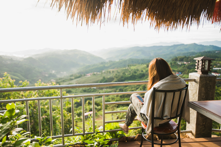 young woman sitting on the chair at mountainの写真素材
