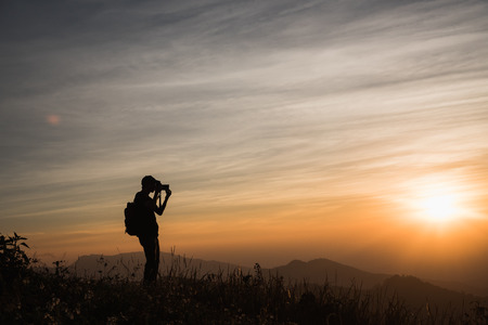 Photographers Silhouettes On Cliff Against Colorful Twilight Skyの写真素材
