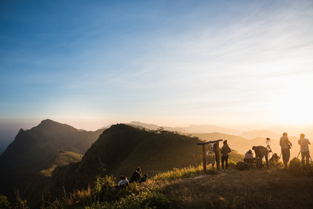 tourists with taking photo of a valley from top of a mountainの写真素材