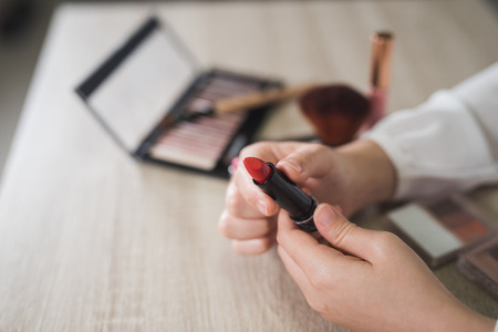 Hand women holding red lipstick on the wood tableの写真素材