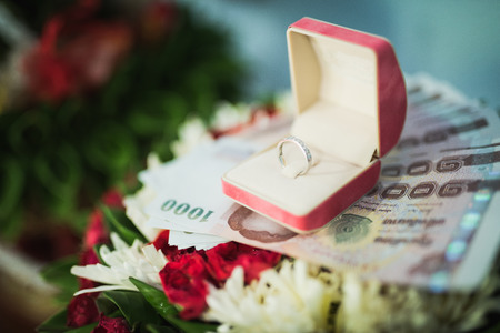 A diamond wedding ring in an open box on traditional Thai style garlandの写真素材