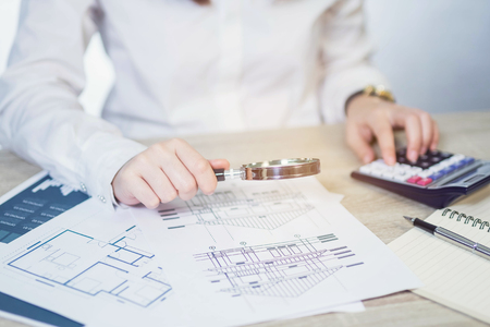 Businesswoman looking through a magnifying with calculatorの写真素材