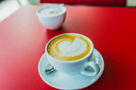 latte art hot coffee on red tableの写真素材