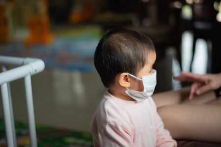 baby wearing surgical mask stay at home. Covid-19 coronavirus conceptの写真素材