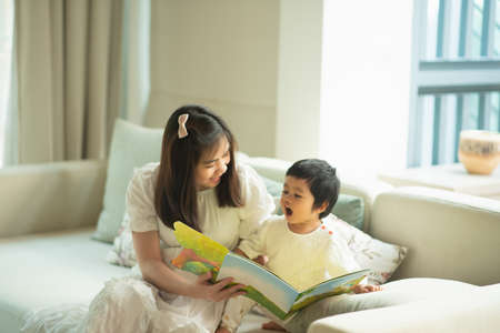 mother and daughter reading a book in the living roomの写真素材