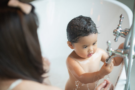 cute baby taking a shower in bathtub