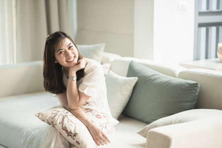 portrait of beautiful girl sitting on the sofa in the living roomの写真素材