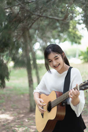 portrait cute girl playing guitar in the gardenの写真素材