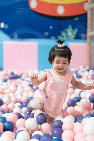 cute asian baby playing a lot of balls at the fun city in department storeの写真素材