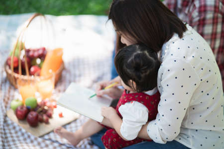 Happy family sitting on the grass during a picnic in a park, family conceptの写真素材