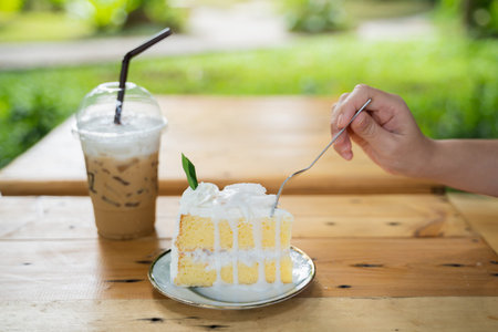 close up of hand cutting coconut cake on wood table