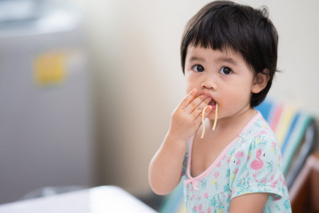 cute asian baby eating spaghetti in the dinning roomの写真素材