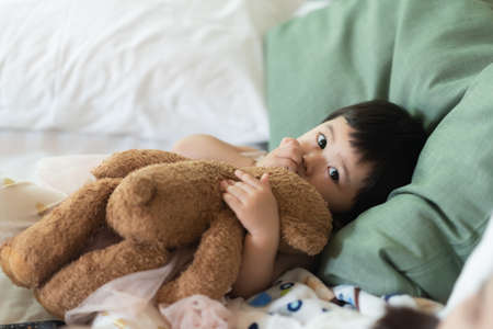 cute baby sucking finger and sleep on the bedの写真素材