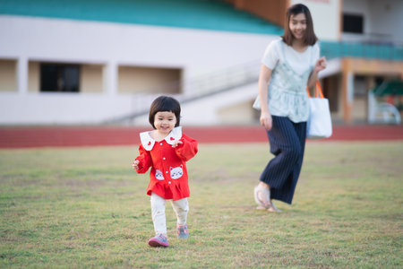 cute baby running with mother at the stadiumの写真素材