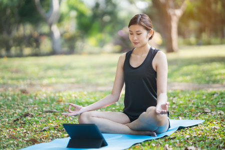 Young woman doing yoga exercise outdoor in the park, sport yoga conceptの写真素材