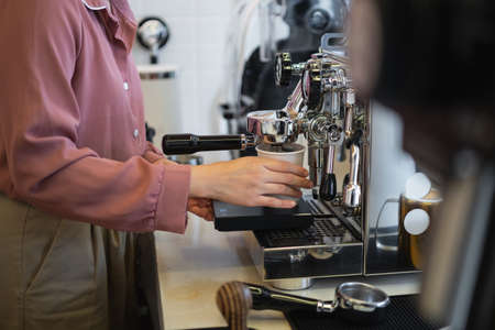 Female barista making coffee in a coffee machine, coffee making conceptの写真素材