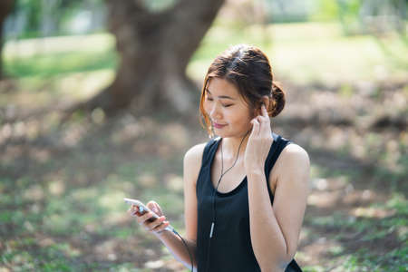 sport women listening music with earphones in the gardenの写真素材