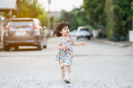 happy cute girl smiling and running on the roadの写真素材