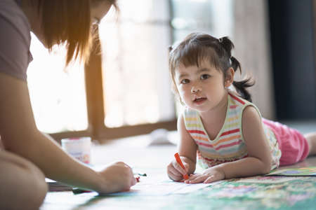 cute baby girl painting with her mother at the houseの写真素材