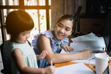 cute baby working with her mother on working tableの写真素材
