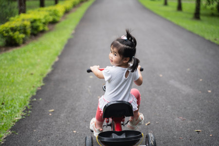 cute baby riding bicycle in the gardenの写真素材