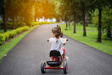 cute baby riding bicycle in the gardenの写真素材