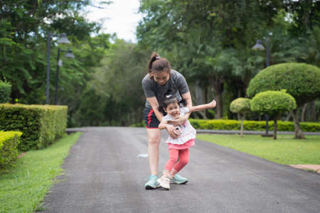 cute baby running with her mother in the garden, family happy conceptの写真素材