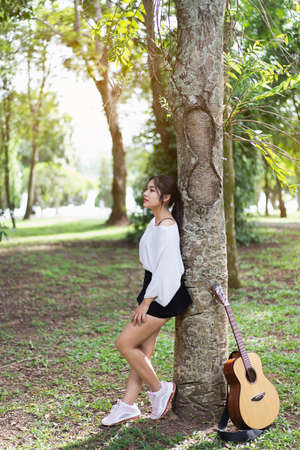beautiful girl playing guitar at the gardenの写真素材