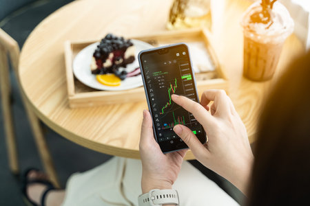 Woman is checking Bitcoin price chart on digital exchange on smartphone in the cafe