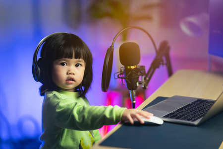 cute baby girl singing with headphone recording new song with microphone in the home recording studioの写真素材