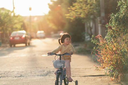 Asian toddler girl child learning to ride bicycle in sunny summer day, kid cycling at park, baby sport conceptの写真素材