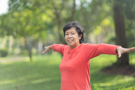 Senior asian woman body warming before exercising. Old woman stretching before jogging in garden, Sport athlete running concept.の写真素材
