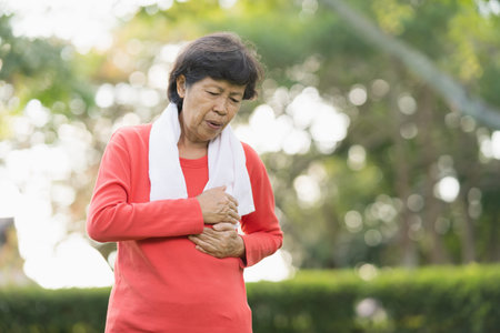 Senior asian woman suffer from exercise pain. Senior woman having heart attack after exercise at park. Health conceptの写真素材