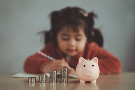 Family Saving money. Asian baby girl daughter plan to spend the future in earnest, finance and saving, family and financial concept.の写真素材