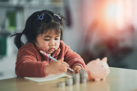 Family Saving money. Asian baby girl daughter plan to spend the future in earnest, finance and saving, family and financial concept.の写真素材