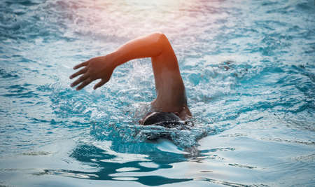Sport man swimmer in cap breathing performing the butterfly stroke. Swimmer swimming at the pool. Sport swimming concept.の写真素材