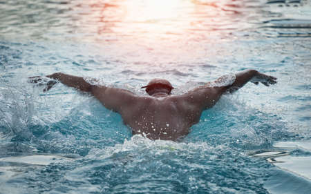 Sport man swimmer in cap breathing performing the butterfly stroke. Swimmer swimming at the pool. Sport swimming concept.の写真素材