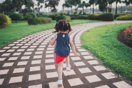 Happy baby asian girl smiling. little girl running at sunset happy baby girl smiling. little girl running at sunset. cute baby girl running at playground garden.の写真素材