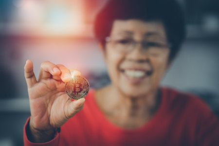 Senior woman smiling holding bitcoin cryptocurrency as electronic payment,   technology money market conceptの写真素材
