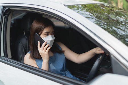 Asian woman wearing surgical mask while driving car. During pandemic wearing a mask when you driving...