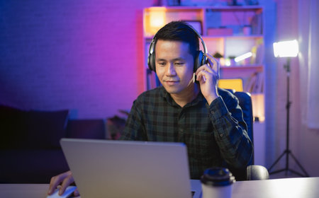 Asian influencer man smile live streaming or working conferrence with laptop and wearing headphone....