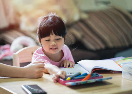 Cute little child painting with colorful paints. Asian girl using crayon drawing color.Baby artist activity lifestyle concept.の写真素材
