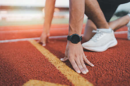 Athlete sportman runner training run on lane at the stadium in morning. Runner man wearing white vest to practice running prepare for competition race. Sport concept.の写真素材