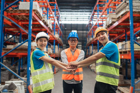 Group of industrial warehouse asian worker in safety suite hand stack celebrate successful or deal commitment. Logistics , supply chain and warehouse business.Teamwork unity under view concept.の写真素材