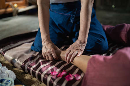Massage and spa relaxing treatment of office syndrome traditional thai massage style. Asain senior female masseuse doing massage treat hand, back pain, arm pain, foot and stress for old woman tired.の写真素材