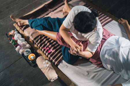 Massage and spa relaxing treatment of office syndrome traditional thai massage style. Asain senior female masseuse doing massage treat hand, back pain, arm pain, foot and stress for old woman tired.の写真素材