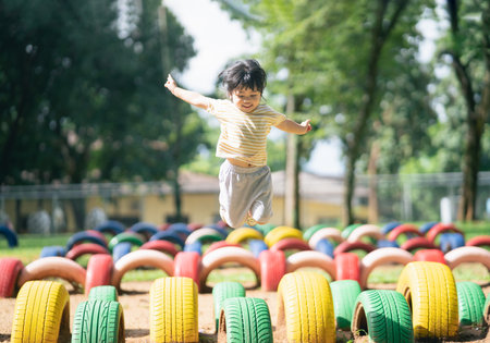 Cute asian girl smile and play on school or kindergarten yard or playground. Healthy summer activity for children. Little asian girl climbing outdoors at playground. Child playing on outdoor playground.の写真素材