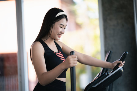 Asian sportswoman exercising on elliptical machine in the gym, determination to cardio lose weight, makes her healthy. exercise elliptical machine woman fitness sport concept.の写真素材