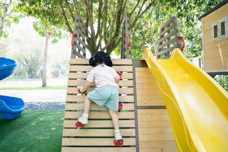 Cute asian girl smile climbing ladder and play on school or kindergarten yard or playground. Healthy summer activity for children. Little asian girl funny happy. Child playing on outdoor playground.の写真素材
