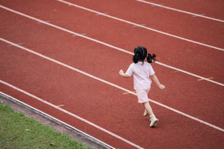 Baby asian girl run jogging at running track, running field at stadium. little girl running at sunset happy baby girl smiling. little girl running at sunset. cute baby girl running at running track.の写真素材